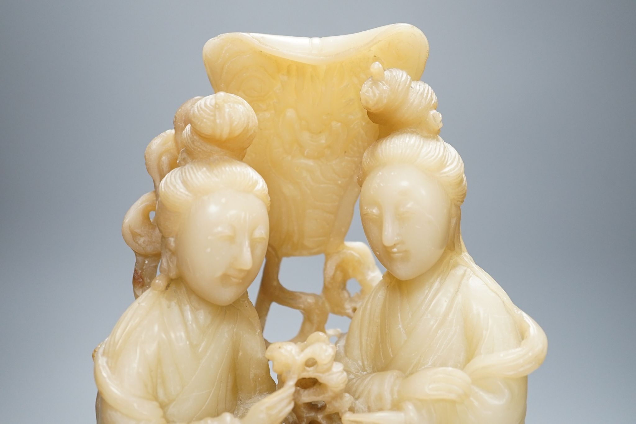 A Chinese soapstone carving of two ladies, wood stand, early 20th century, 36 cms high.